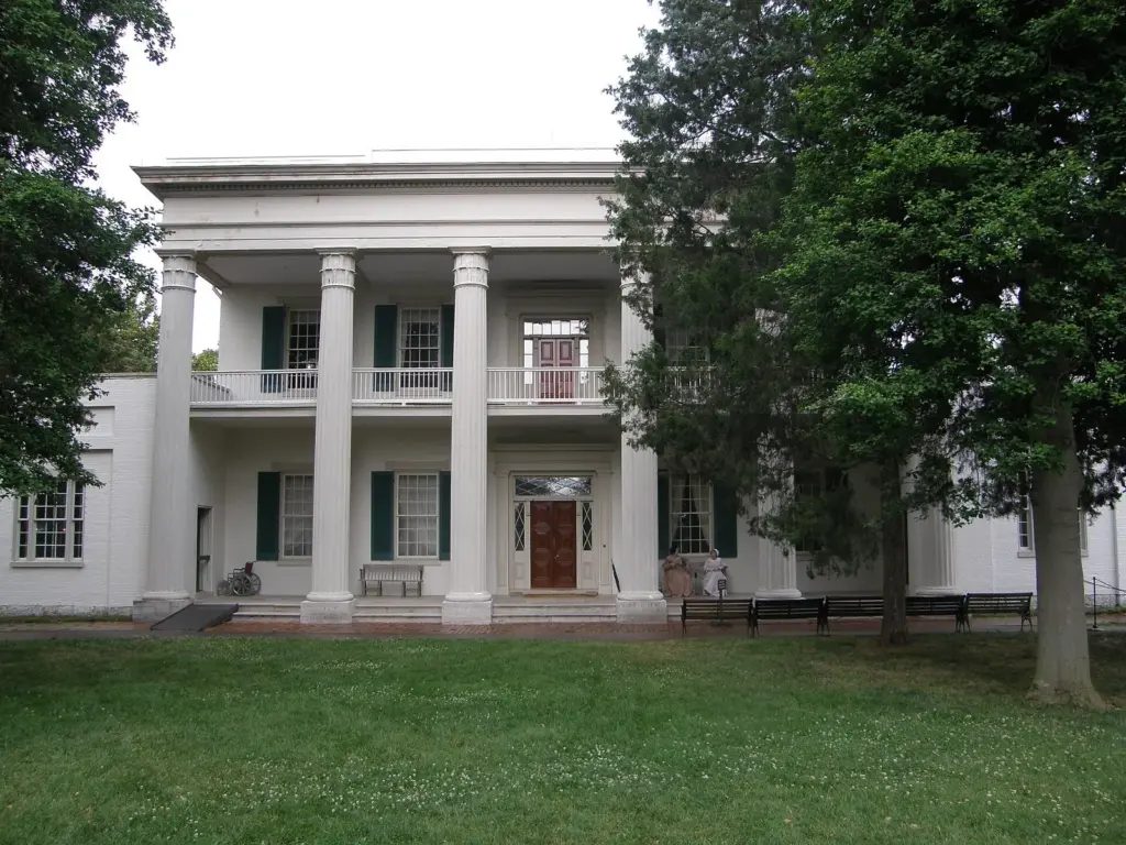 The white-columned front of Andrew Jackson's Hermitage mansion behind a lawn and trees