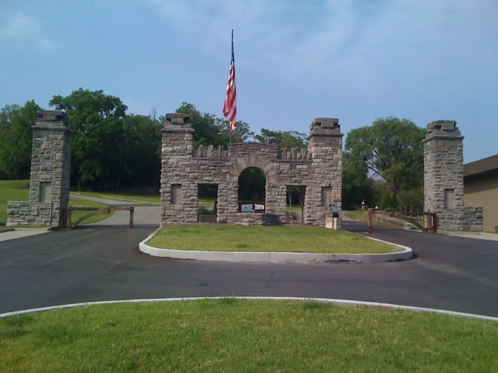 A stone gateway with square pillars and an American flag flying above it at the entrance to Fort Negley Park