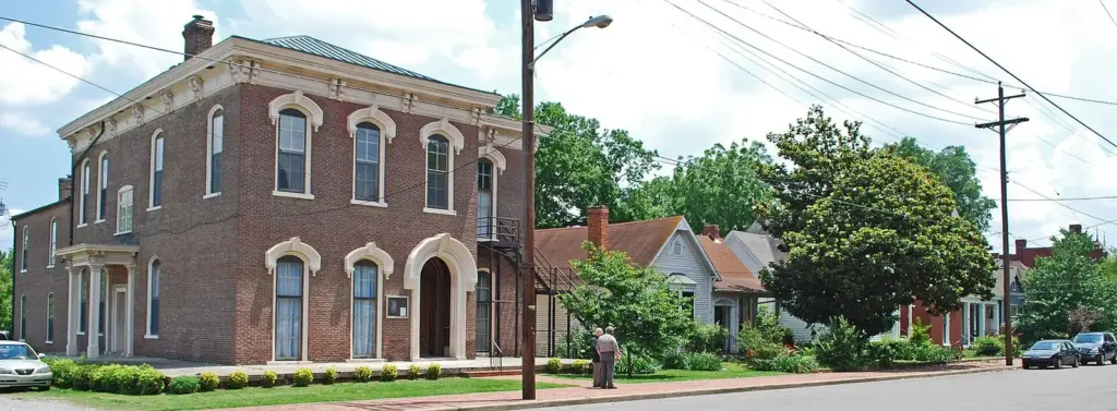 A row of restored red-brick Victorian and Italianate houses along a tree-lined street in Germantown