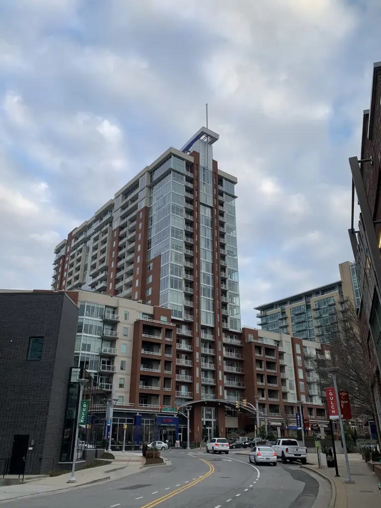 A tall residential tower rising above shops and a street in the Gulch neighborhood