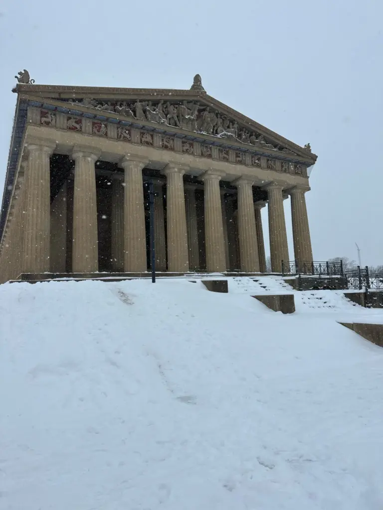The Parthenon in Centennial Park with snow covering its steps and lawn under a gray sky