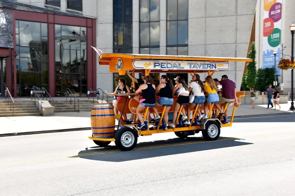 A group of riders pedaling a Nashville Pedal Tavern bike along a downtown street