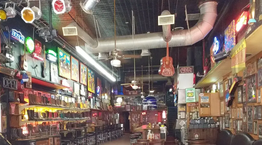 The empty interior of Robert's Western World, with boots on shelves, neon signs and a stage on the left