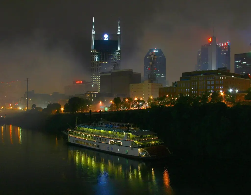 Downtown Nashville towers and a lit-up riverboat on the Cumberland River on a hazy Fourth of July night
