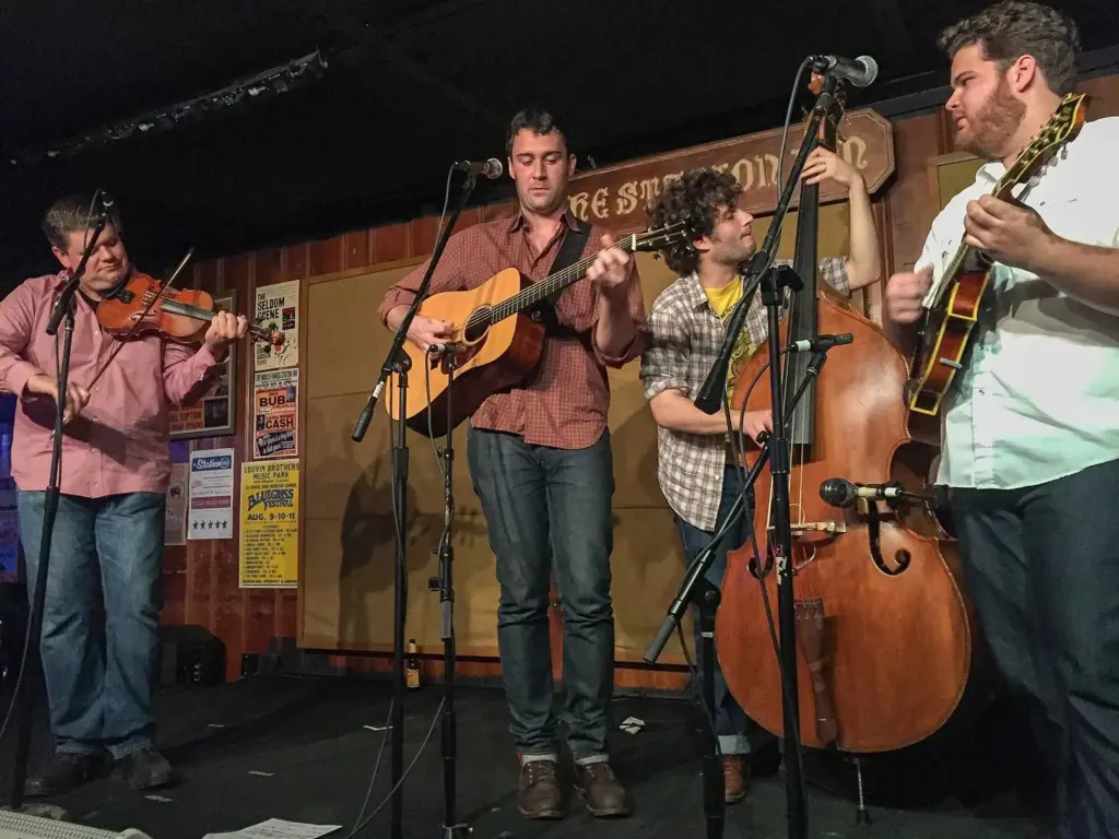 A bluegrass band with fiddle, guitars, mandolin and upright bass playing on the stage of the Station Inn