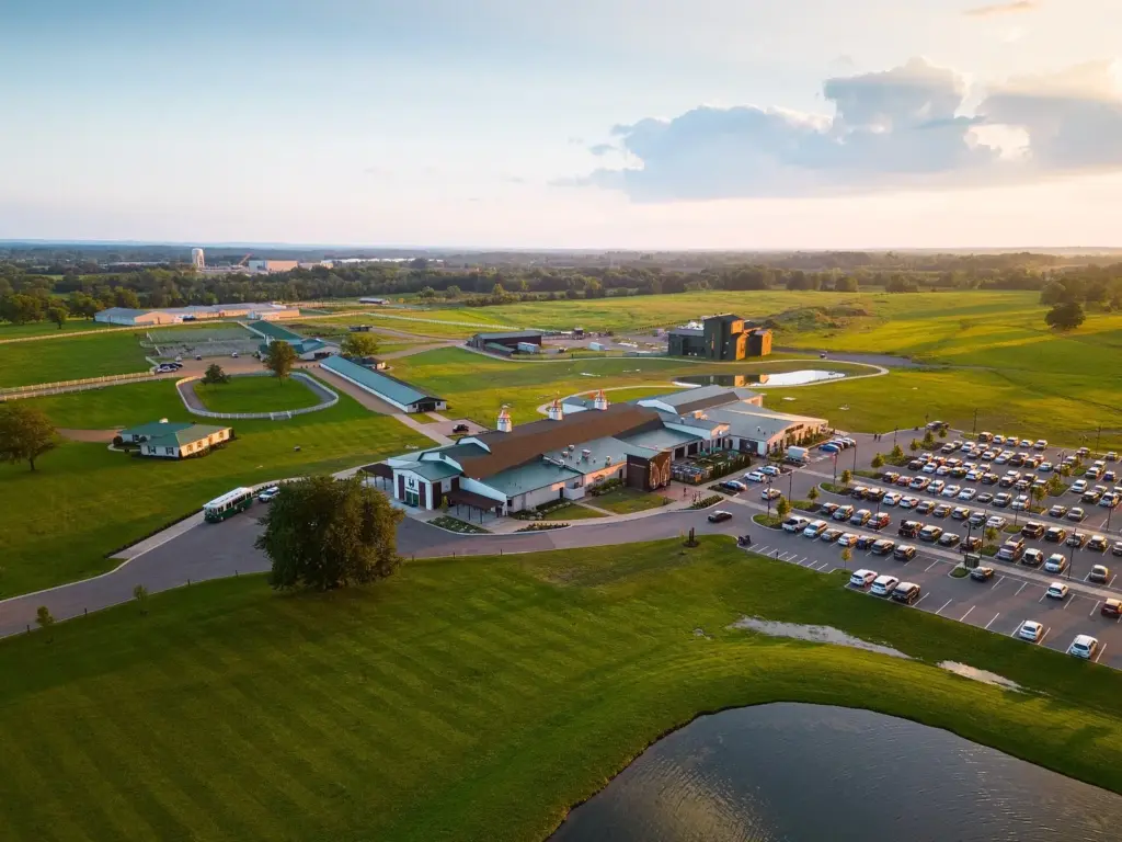 Aerial view at sunset of the Nearest Green Distillery campus in Shelbyville, with barn-style buildings, lawns, a pond and a full parking lot