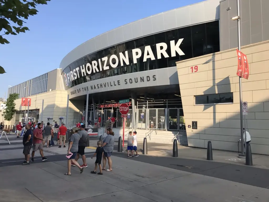 Fans walking toward the curved First Horizon Park entrance on a sunny afternoon