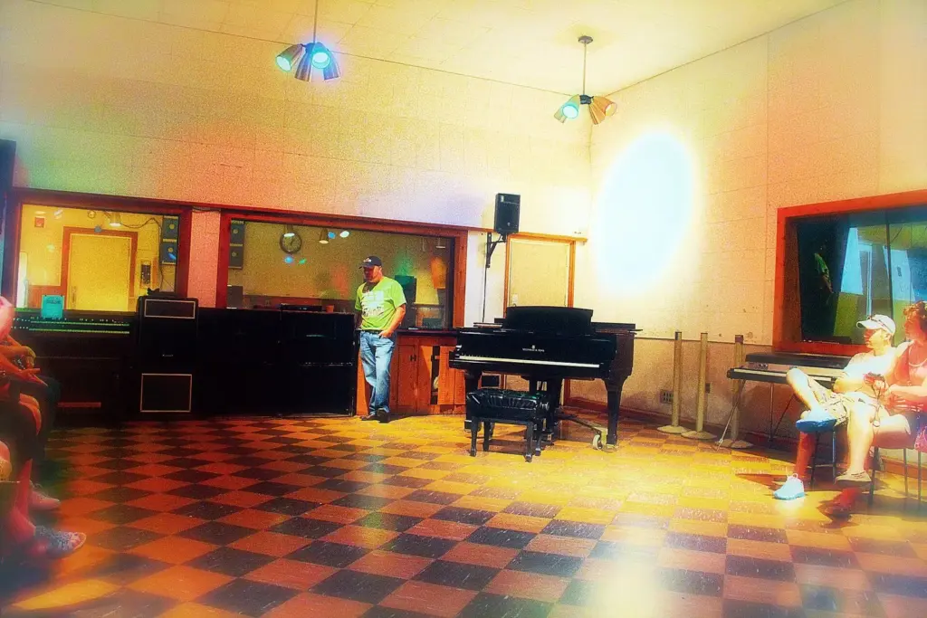 The main recording room at RCA Studio B with a grand piano, a checkerboard floor and colored lights